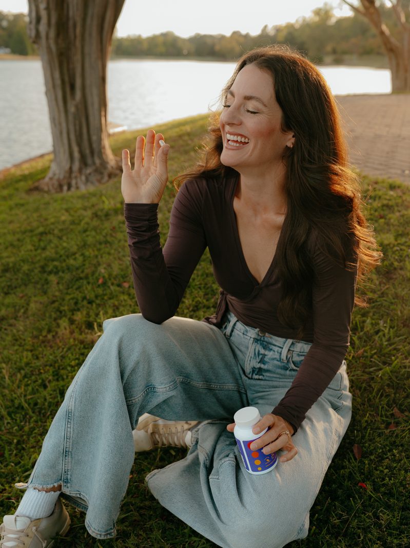 Lyndsay laughing on the grass with a bottle of shePRE